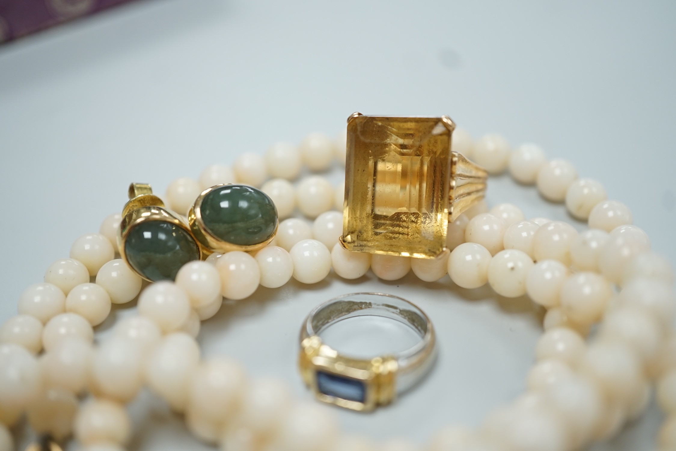 A modern 18k and single stone sapphire set child's ring, size G, a yellow metal and citrine set ring, size J, a pair of 585 and green cabochon set ear studs and a simulated coral bead necklace.